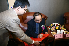 中國質量檢驗協會會員工作部副主任張百熙(左一)在活動現場懇請全國政協副主席阿不來提·阿不都熱西提(右一)為“全國質量知識競賽”決賽活動簽名留念